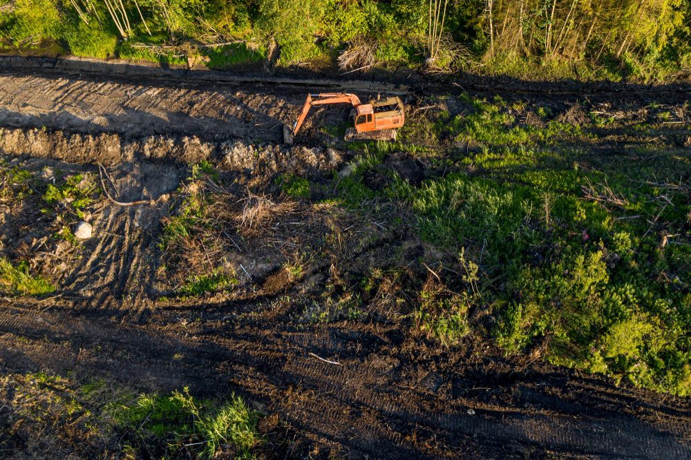 Aerial view of an excavator clearing and grading raw land